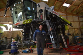 Un homme devant une moissonneuse-batteuse démontée pour effectuer l'entretien