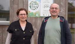 Une femme et un homme devant une pancarte "ici ferme bio"