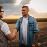 Un agriculteur serre la main d'un partenaire dans un champ