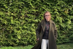 Une jeune femme devant une haie