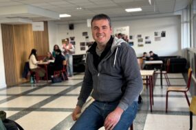 Un homme souriant dans le foyer d'un établissement scolaire