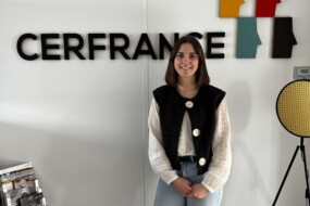 Une jeune femme pose devant un mur avec le logo Cerfrance