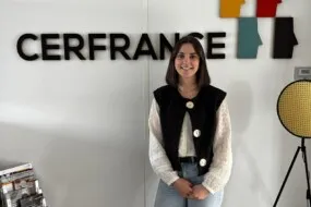 Une jeune femme pose devant un mur avec le logo Cerfrance