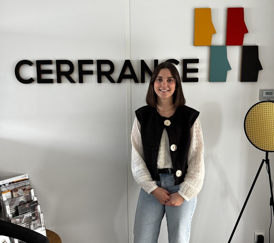 Une jeune femme pose devant un mur avec le logo Cerfrance - Illustration « À l’aise dans mon milieu professionnel »