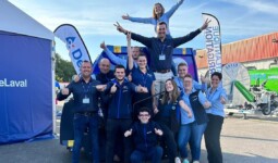 Des commerciaux font une pyramide humaine sur un parking d'une concession agricole