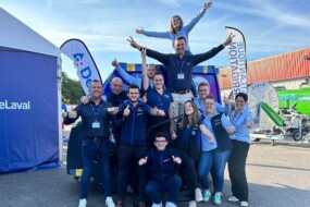 Des commerciaux font une pyramide humaine sur un parking d'une concession agricole