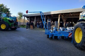 Des tracteurs, du métériel agricole et des personnes dans une cour de ferme