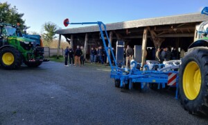 Des tracteurs, du métériel agricole et des personnes dans une cour de ferme