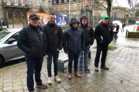 Cinq hommes sur un trottoir par un temps pluvieux