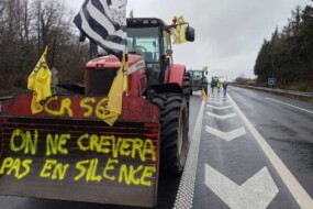 Un tracteur avec un godet et une inscription jaune "on ne crèvera pas en silence" dans le godet