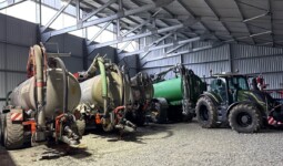 Des tonnes à lisier et un tracteurs dans un hangar à matériel agricole