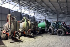 Des tonnes à lisier et un tracteurs dans un hangar à matériel agricole