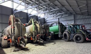 Des tonnes à lisier et un tracteurs dans un hangar à matériel agricole