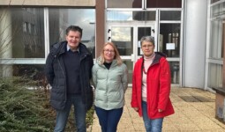 Un homme et deux femmes devant un bâtiment institutionnel