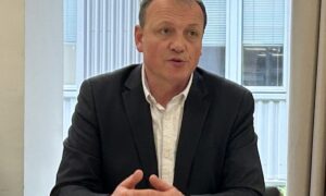 Un homme assis à une table en train de parler avec les mains croisées sur la table