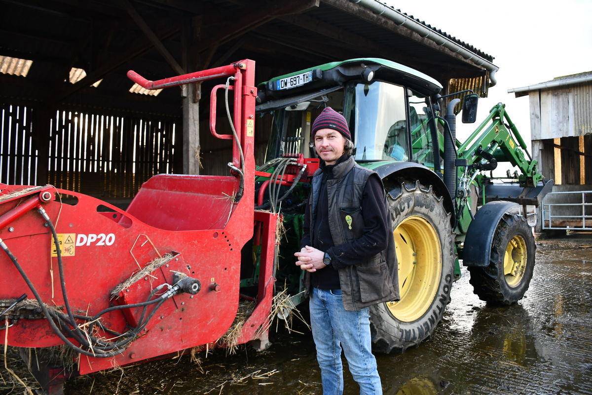 un éleveur devant une dérouleuse-pailleuse