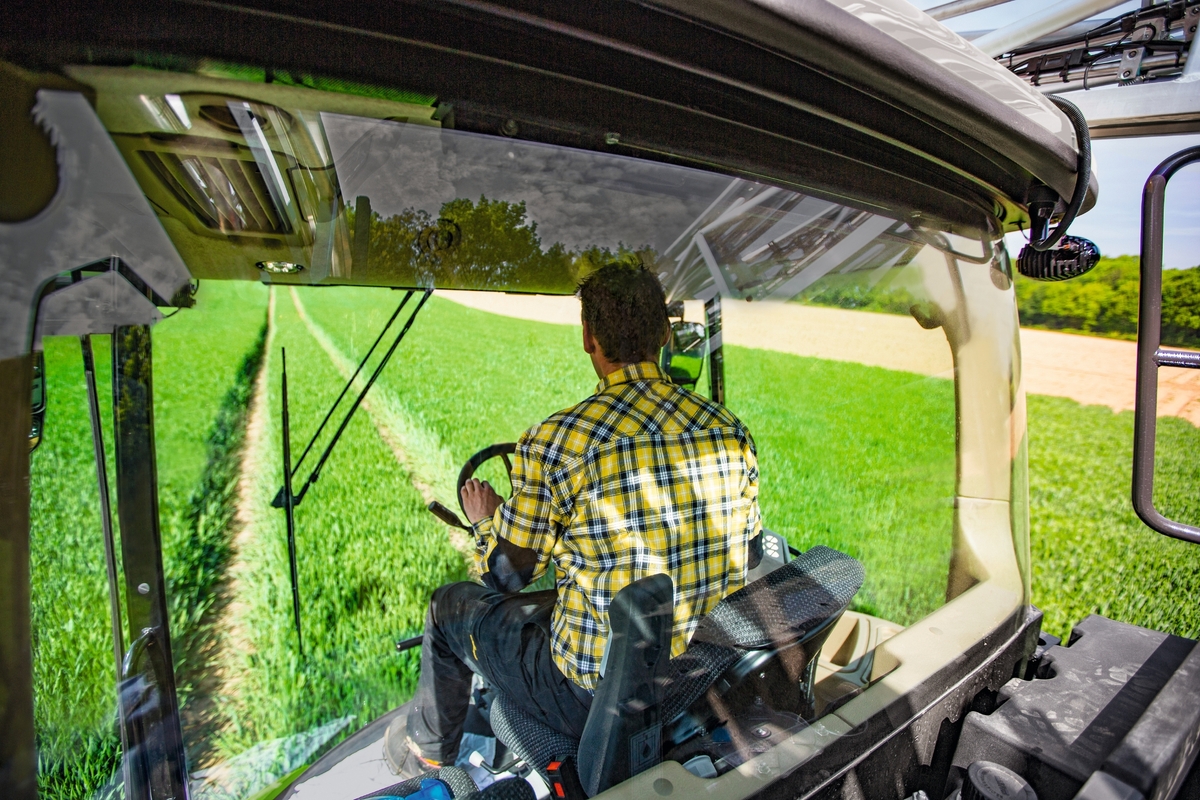 Un homme de dos dans une cabine de pulvérisateur automoteur