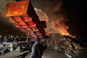 Une remorque en train de décharger des matériaux lors dun' manifestation agricole alors que le ciel est rempli de fumée