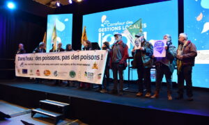 Des hommes et femmes portent une banderole sur un podium