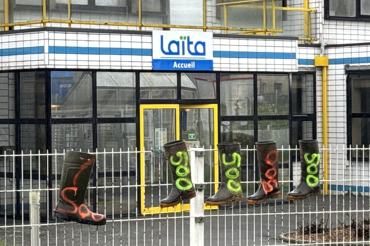 Des bottes en caoutchouc avec l'inscription 500 accrochées sur les grilles devant le bâtiment de l'entreprise laitière Laïta - Illustration « Nous avons besoin d’un lait payé à 500 € / 1 000 L »