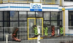 Des bottes en caoutchouc avec l'inscription 500 accrochées sur les grilles devant le bâtiment de l'entreprise laitière Laïta