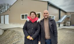 une femme et un homme devant un bâtiment de poules pondeuses
