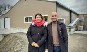une femme et un homme devant un bâtiment de poules pondeuses