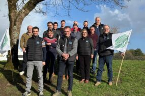 Un groupe de personne sous un arbre dans un champ avec des drapeaux de la FDSEA