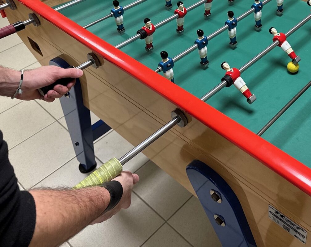 Des mains sur les barres d'un baby-foot