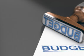 Une feuille et un tampon à encre "Budget" sur une table. Le tampon bleu a été aposé sur la feuille.