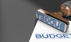 Une feuille et un tampon à encre "Budget" sur une table. Le tampon bleu a été aposé sur la feuille.