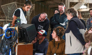 Un tournage de film dans une ferme avec des hommes et des femmes qui regardent la scène sur un écran