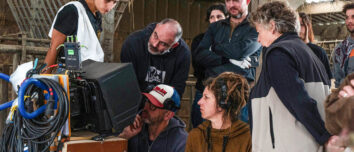 Un tournage de film dans une ferme avec des hommes et des femmes qui regardent la scène sur un écran