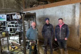 Trois hommes à côté d'une cage de parage pour bovins