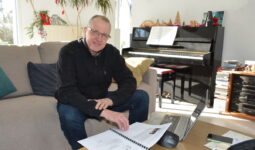 Un homme dans un camapé en train de travailler sur une table basse avec un piano derrière