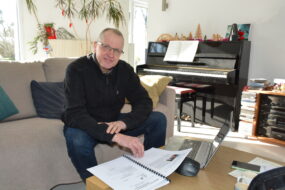 Un homme dans un camapé en train de travailler sur une table basse avec un piano derrière
