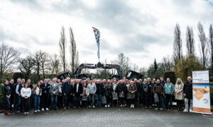 Un groupe de personnes devant 2 tracteurs avec des godets qui forment une arche
