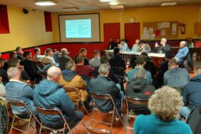 Une réunion rassemblant des gens face à des personnes assises derrière une table