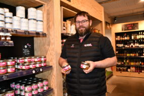 un homme tient des boîtes de pâté devant des étagères
