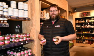un homme tient des boîtes de pâté devant des étagères