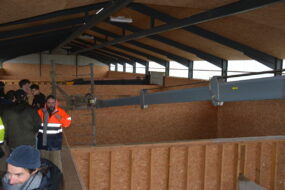 Des personnes visitent un hangar à foin avec cellules de séchage