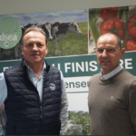 Deux hommes posent devant une affiche