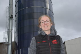 Une femme devant des silos de maïs dans son exploitation porcine