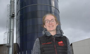 Une femme devant des silos de maïs dans son exploitation porcine