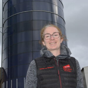 Une femme devant des silos de maïs dans son exploitation porcine