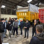 Des personnes devant des remorques agricoles