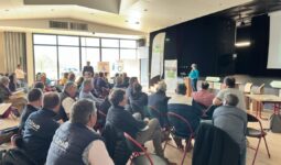 Un groupe de personne dans une salle dont une qui parle à la tribune