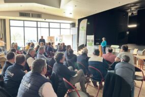 Un groupe de personne dans une salle dont une qui parle à la tribune