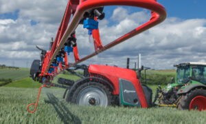 Vue de profil d'un pulvérisateur agricole et d'un tracteur au travail au champ