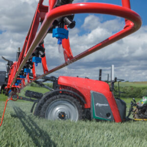 Vue de profil d'un pulvérisateur agricole et d'un tracteur au travail au champ